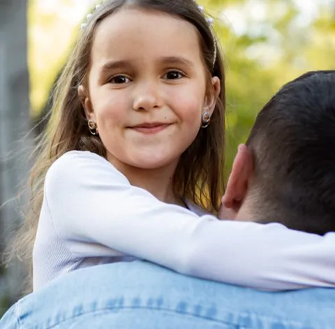 A young girl being carried by her father looking directly into the camera - Safeguarding Children Training Course