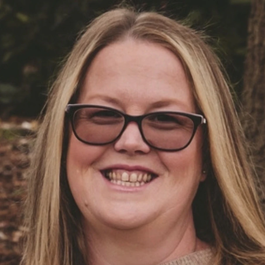 Image of a woman with glasses and long blond hair who is the IQA for Coleman Training